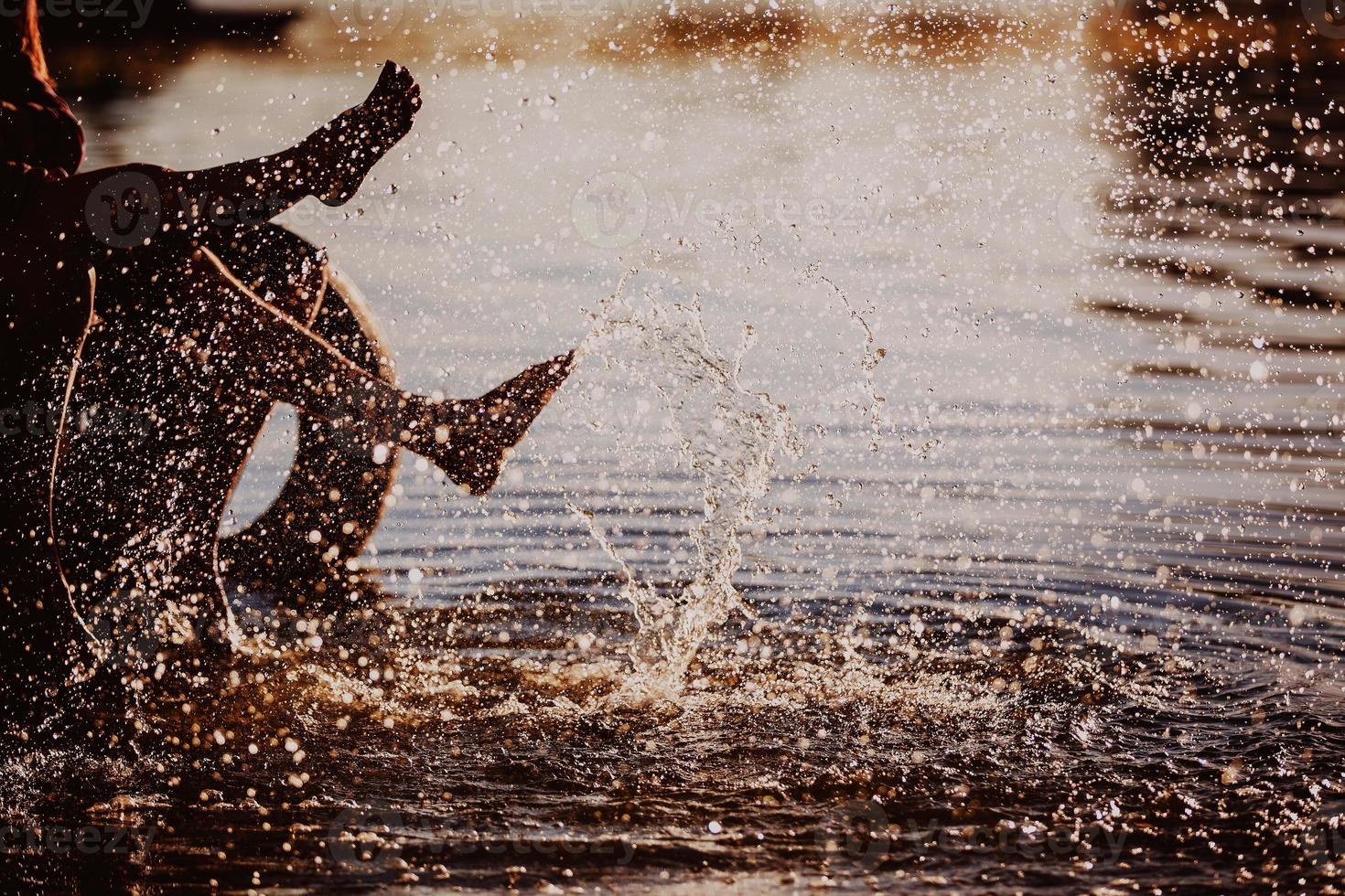 Paar spritzt ihre Füße im Wasser bei Sonnenuntergang foto