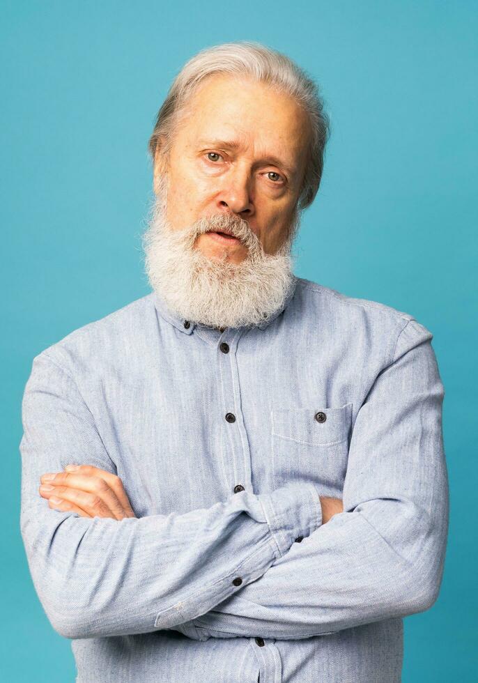 Porträt von unzufrieden mürrisch besoffen aus Senior reifen Mann auf Blau Hintergrund. Negativ Mensch Emotionen, Gesicht Ausdruck Gefühle foto