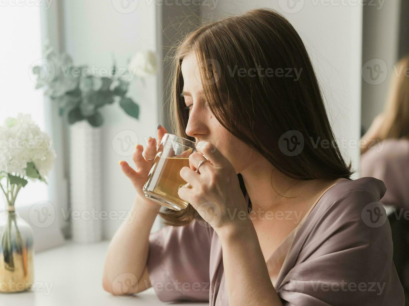 jung Frau Sitzung auf Stuhl beim Zuhause und Trinken Tee, beiläufig Stil Innen- schießen. Nahansicht Porträt foto