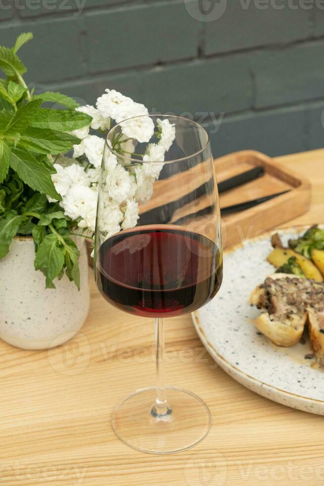 rot Wein im Weinglas auf Tabelle mit gebacken Fleisch im Teig auf Backstein Mauer Hintergrund. foto