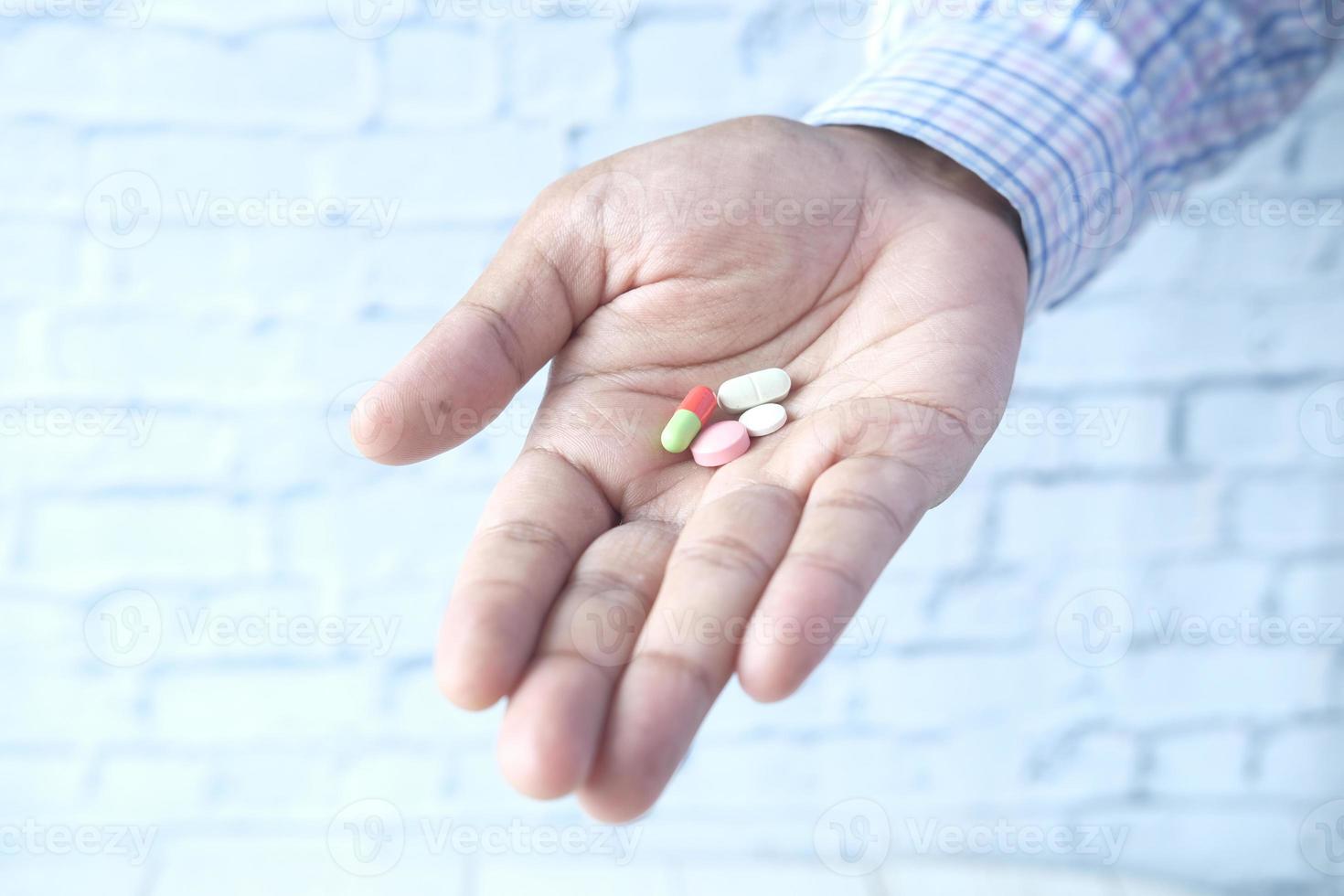 Männerhand mit Medizin aus dem Tablettenbehälter verschüttet foto