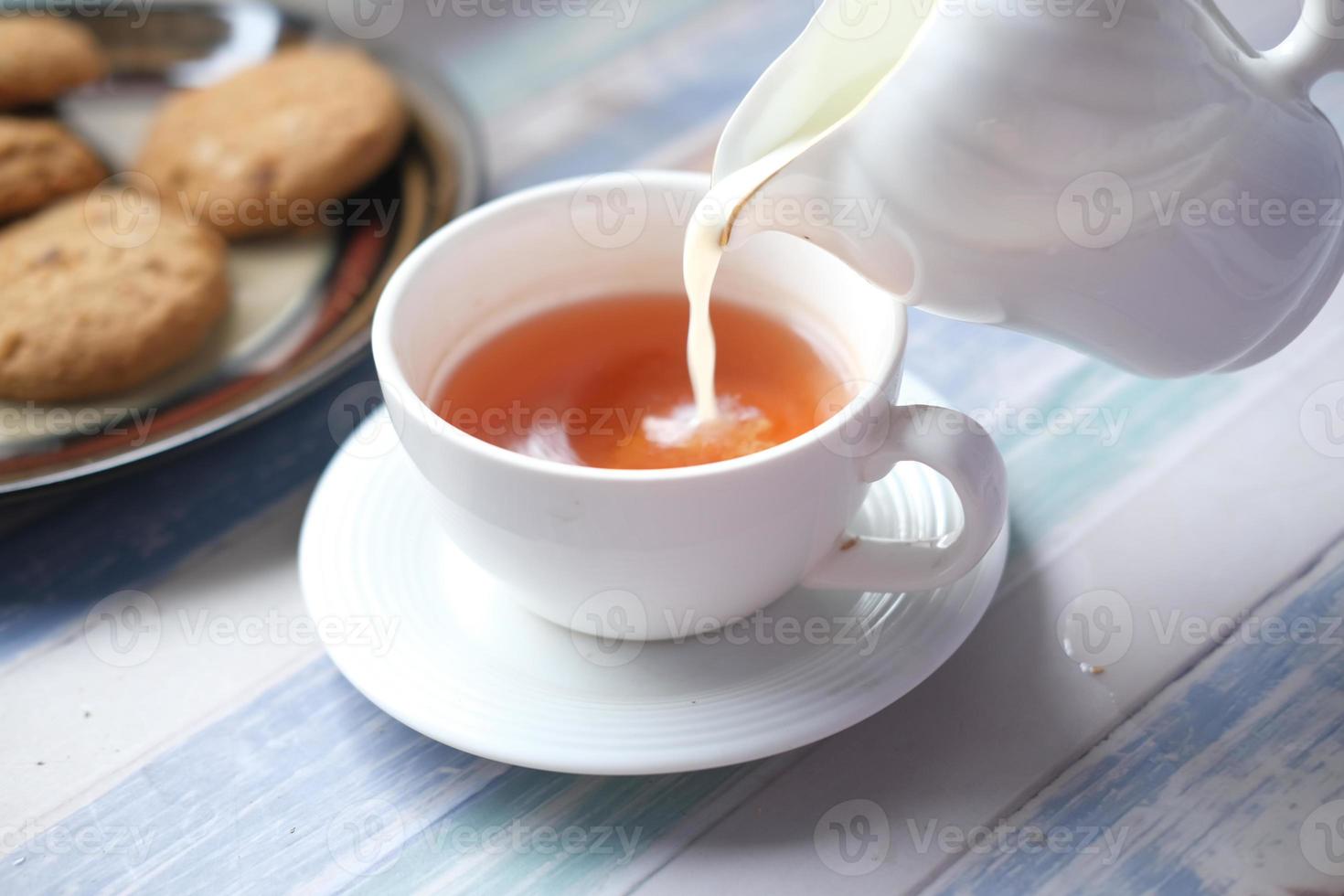 Nahaufnahme von Milch in eine Teetasse gießen? foto