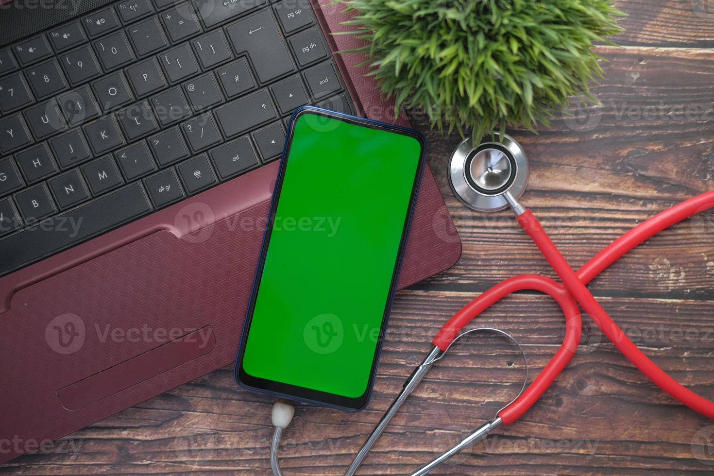 medizinisches Stethoskop und Smartphone auf Laptop auf Holztisch foto