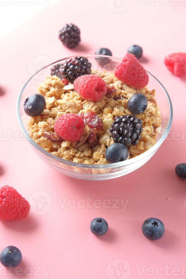 Müsli und Beeren in der Schüssel auf rosa Hintergrund foto