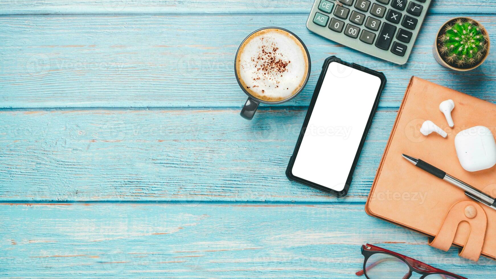 oben Sicht, Büro Schreibtisch mit leer Bildschirm Clever Telefon, Tasse von Kaffee, Stift, Brille und Notizbuch, Kopieren Raum, spotten hoch. foto