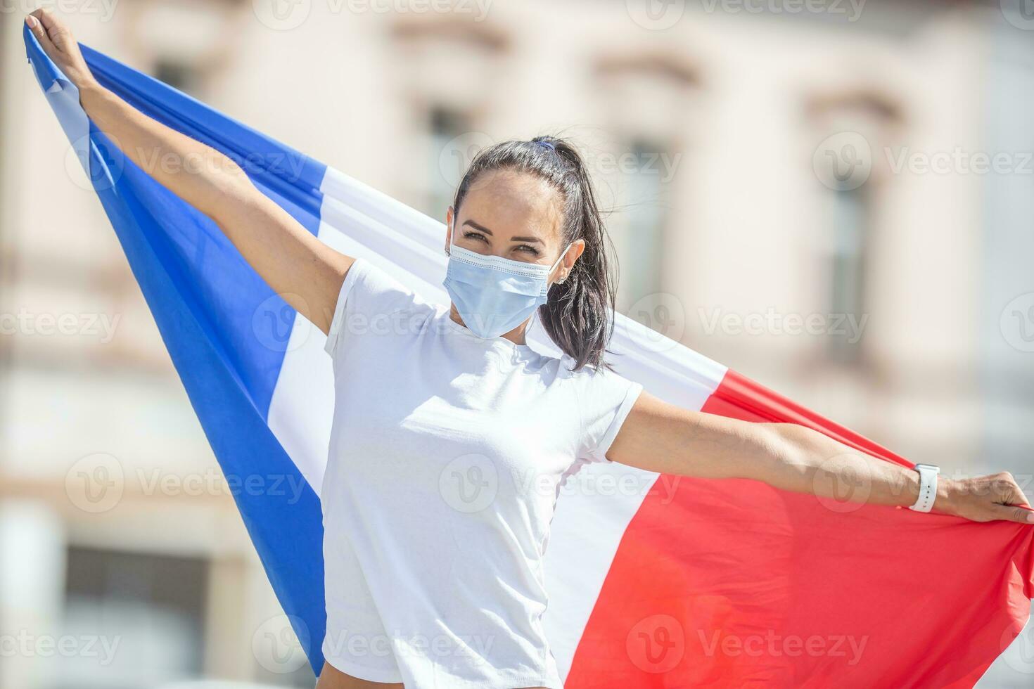 weiblich im ein Gesicht Maske hält ein Französisch Flagge auf das Straße foto