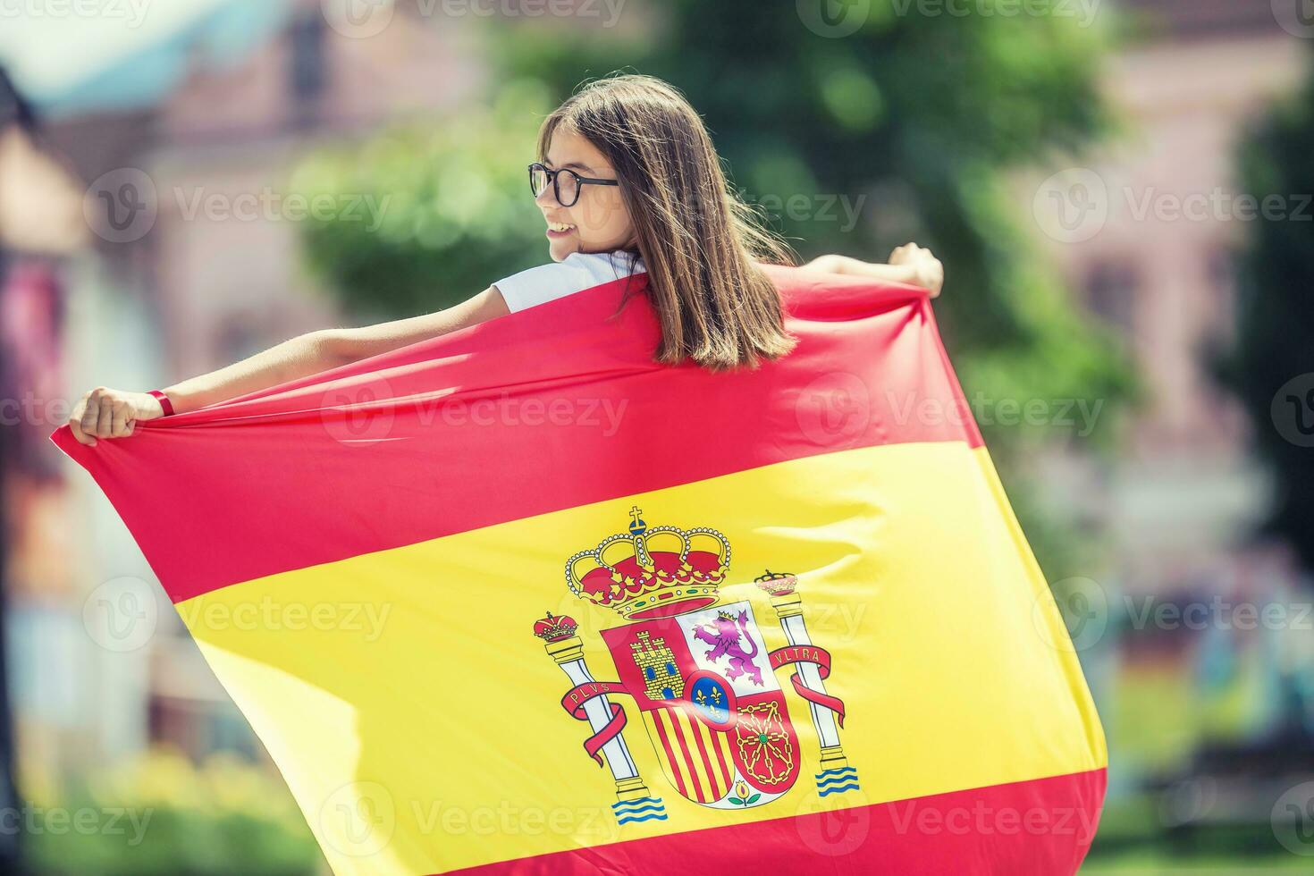 glücklich Mädchen Tourist Gehen im das Straße mit Spanisch Flagge foto
