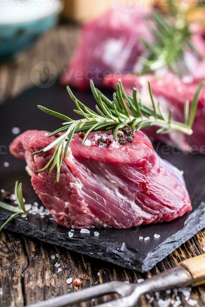 roh Rindfleisch Fleisch. roh Rindfleisch Filet Steak auf ein Schneiden Tafel mit Rosmarin Pfeffer Salz- im andere Positionen. foto