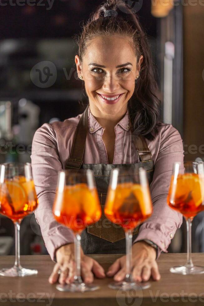 Bardame bietet an Aperol Spritz Cocktails auf ein Bar lächelnd beim das Kamera foto