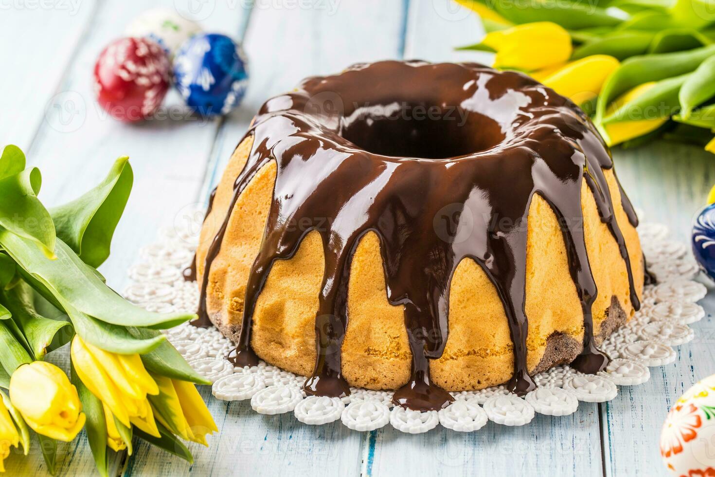 köstlich Urlaub slowakisch und Tschechisch Kuchen Babovka mit Schokolade Glasur. Ostern Dekorationen - - Frühling Tulpen und Eier foto