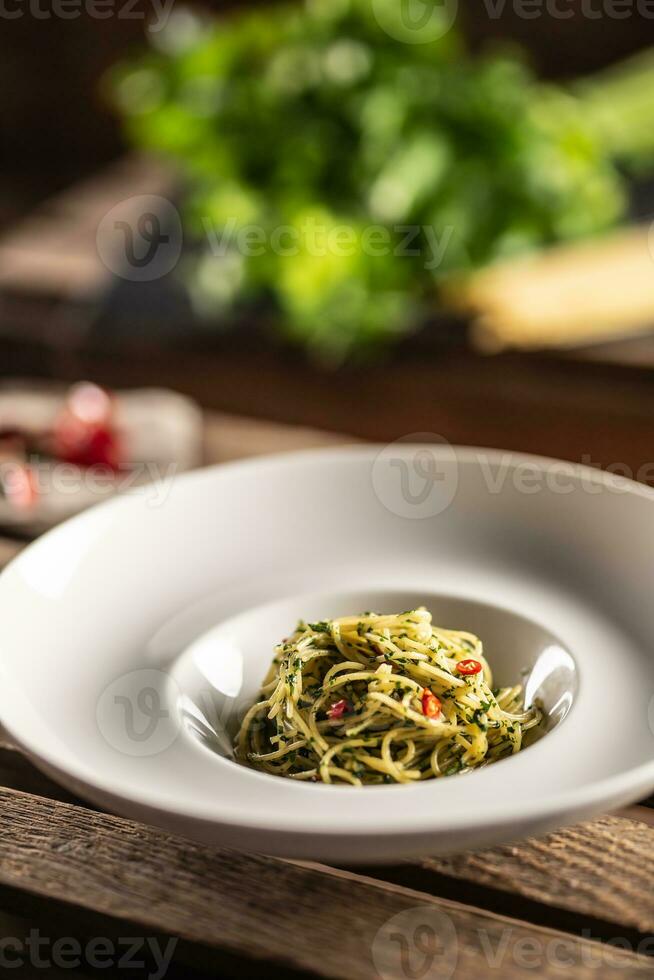 Spaghetti Aglio e olio mit Olive Öl, Gralic, Basilikum,, Tomaten und Peperoni serviert auf ein tief Teller foto