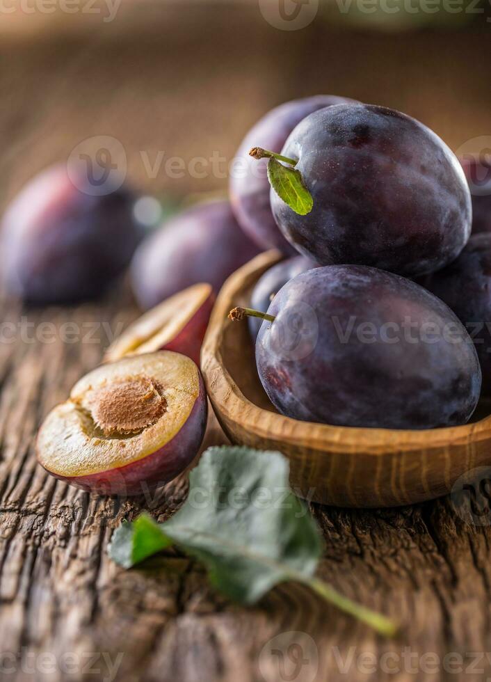 Pflaumen. frisch saftig Pflaumen im ein Schüssel auf ein hölzern oder Beton Tafel foto