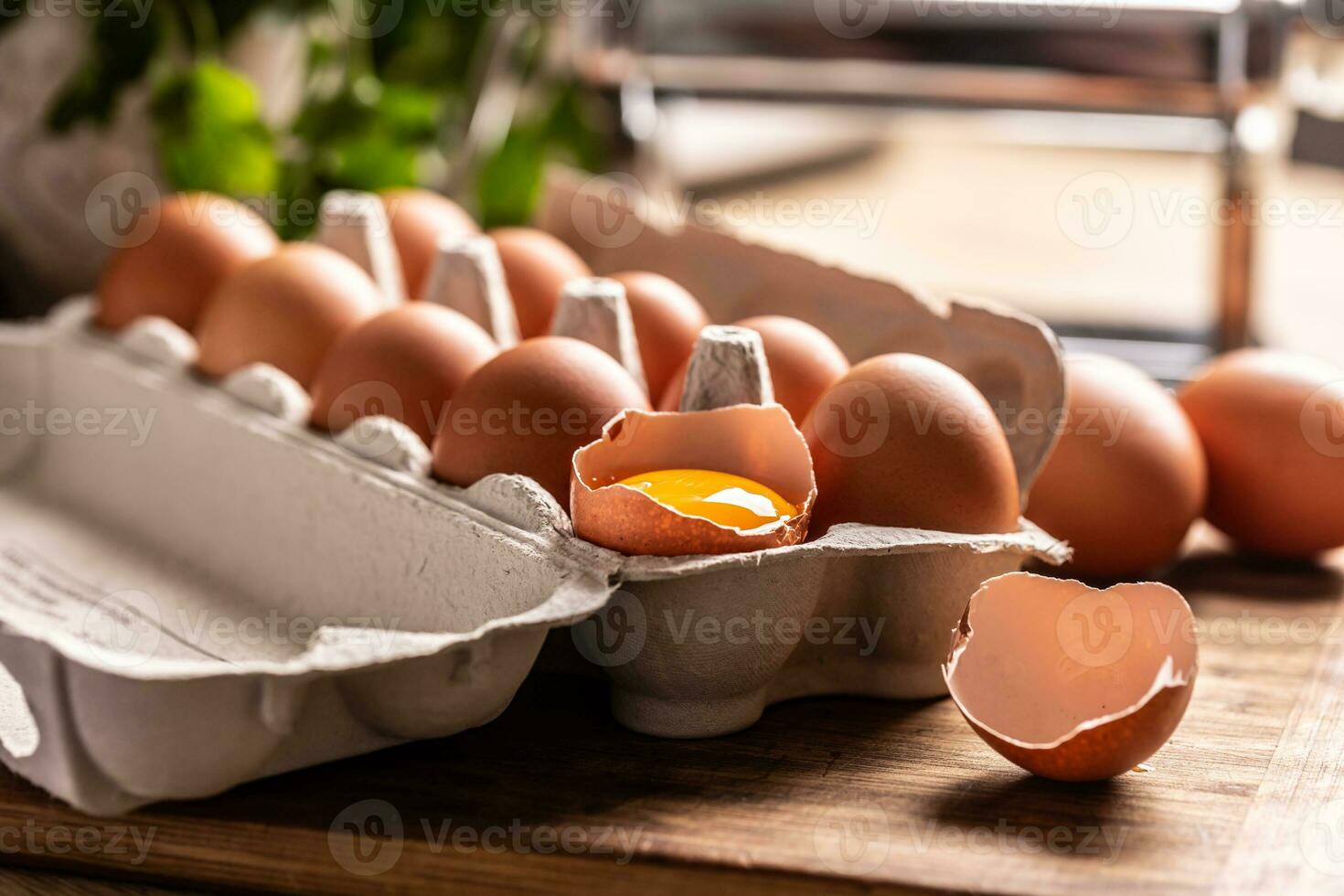 ein Karton Box voll von frisch Hähnchen Eier mit Eigelb im gebrochen Ei auf das Küche Zähler foto