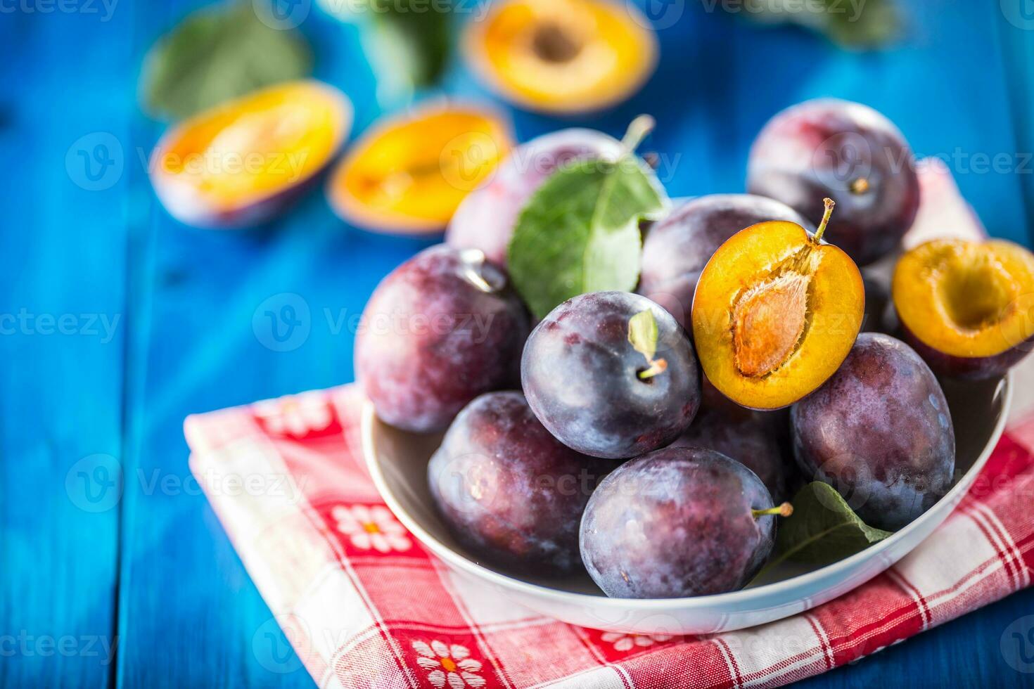 Pflaumen. frisch saftig Pflaumen im ein Schüssel auf ein hölzern oder Beton Tafel foto