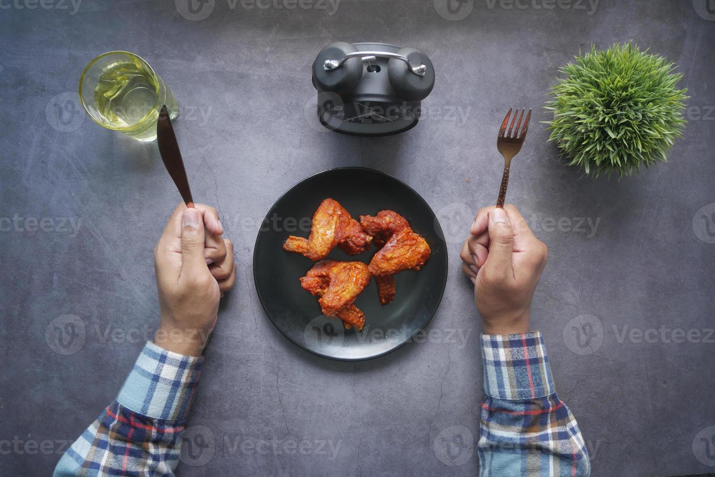 Mans Hände mit Messer und Gabel warten darauf, gebratene Hähnchenfilets auf dem Teller zu essen foto