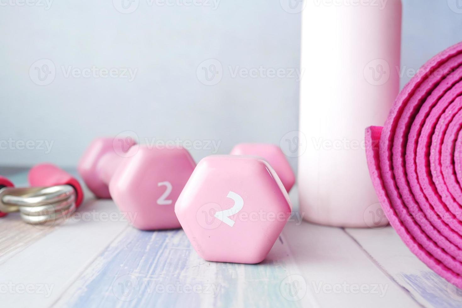 rosafarbene Hantel, Gymnastikmatte und Wasserflasche auf weißem Hintergrund foto