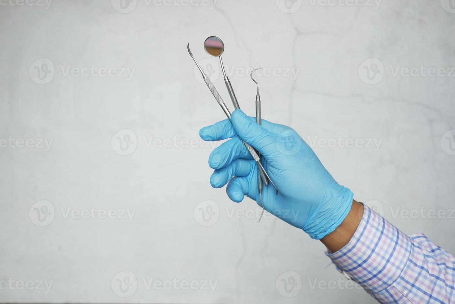 Hand in Latexhandschuhen mit zahnmedizinischer Ausrüstung foto