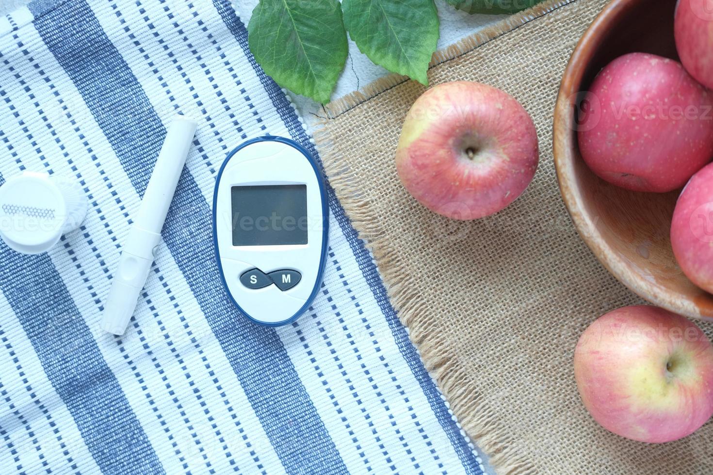 Diabetiker-Messgeräte und frischer Apfel auf dem Tisch foto