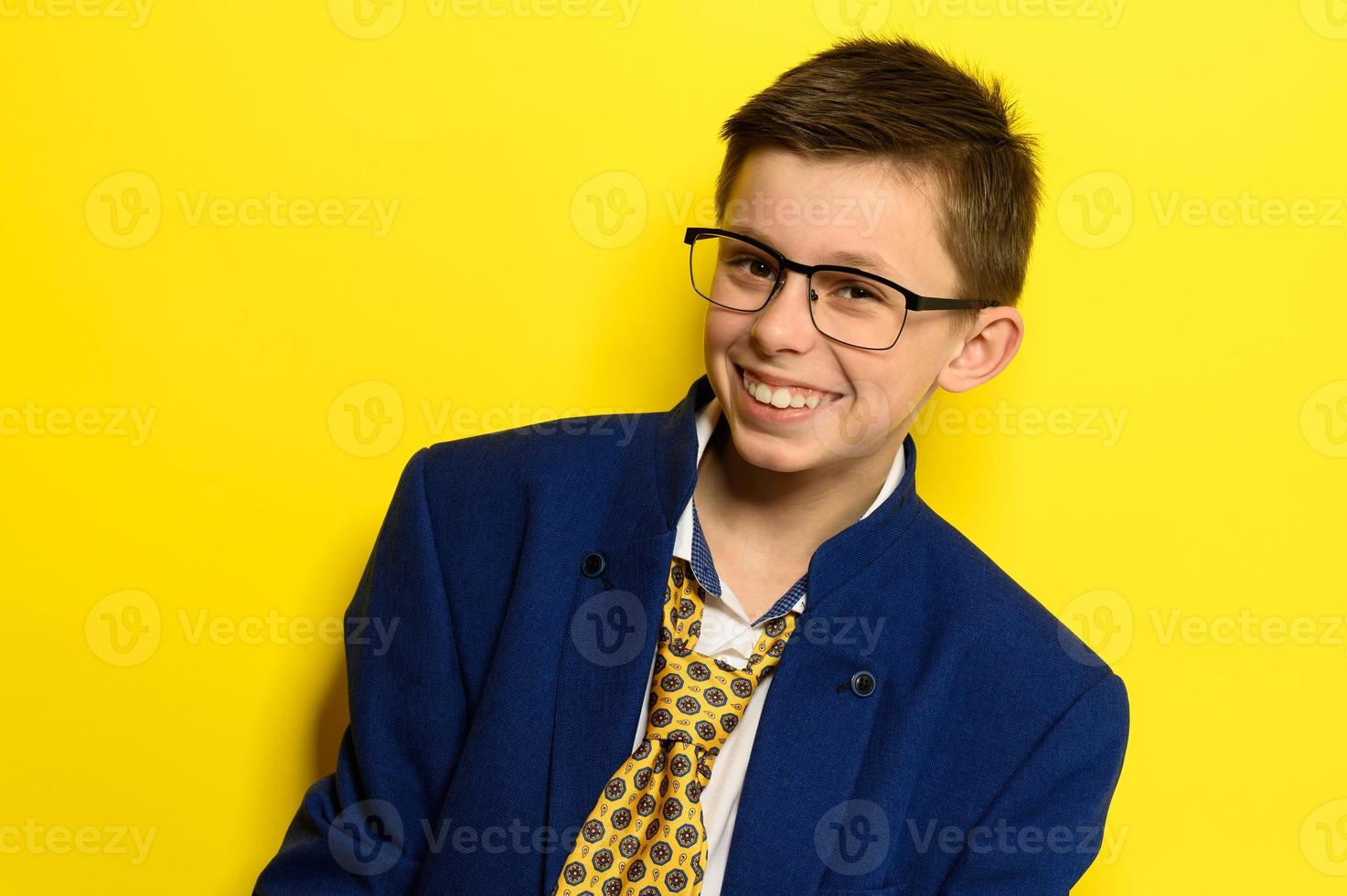 Attraktiver Junge in einem Anzug für Erwachsene auf gelbem Hintergrund, die Vorstellungskraft eines Kindes über das Erwachsenenleben. foto