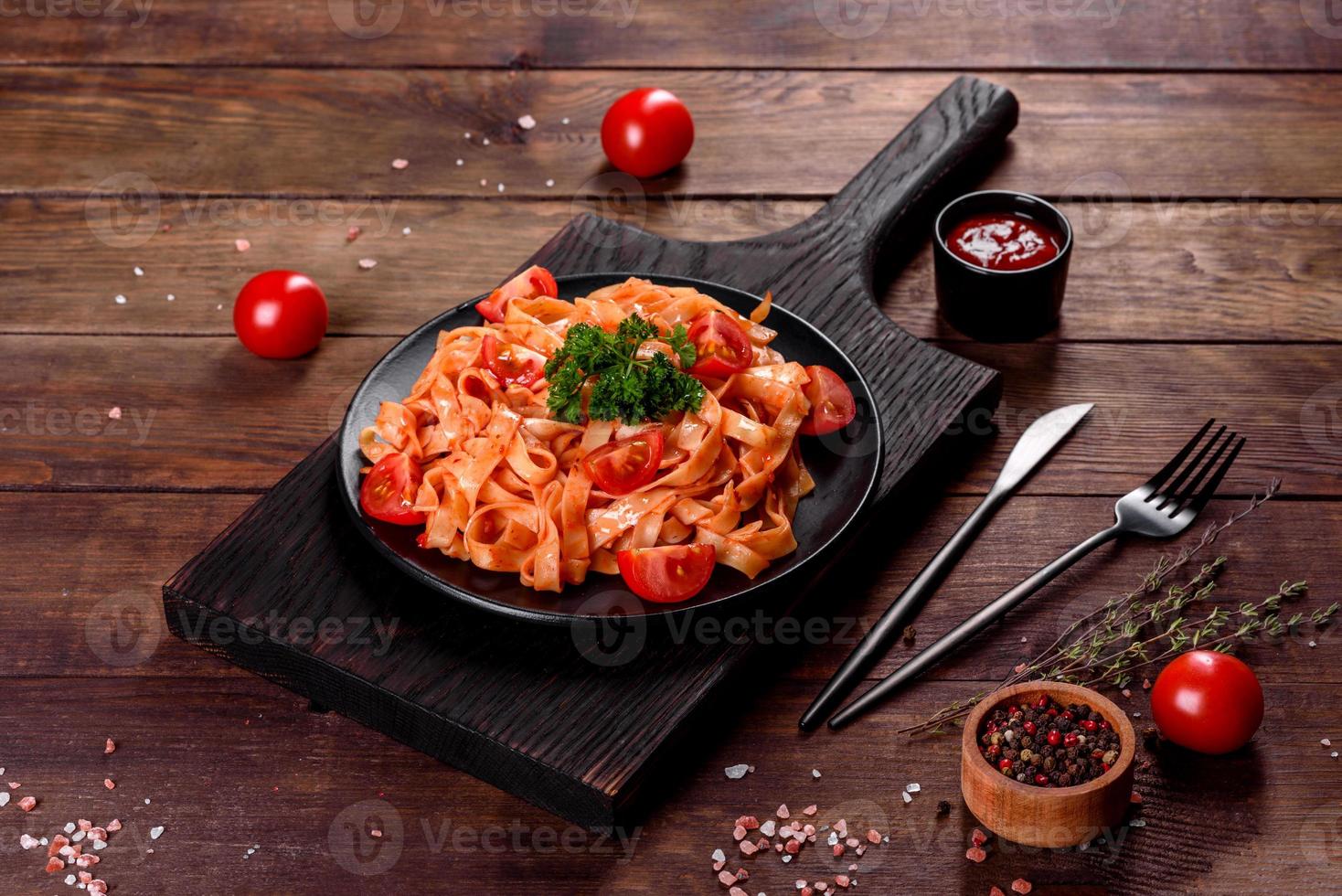 köstliche frische Paste mit Tomatensauce mit Gewürzen und Kräutern auf dunklem Hintergrund foto