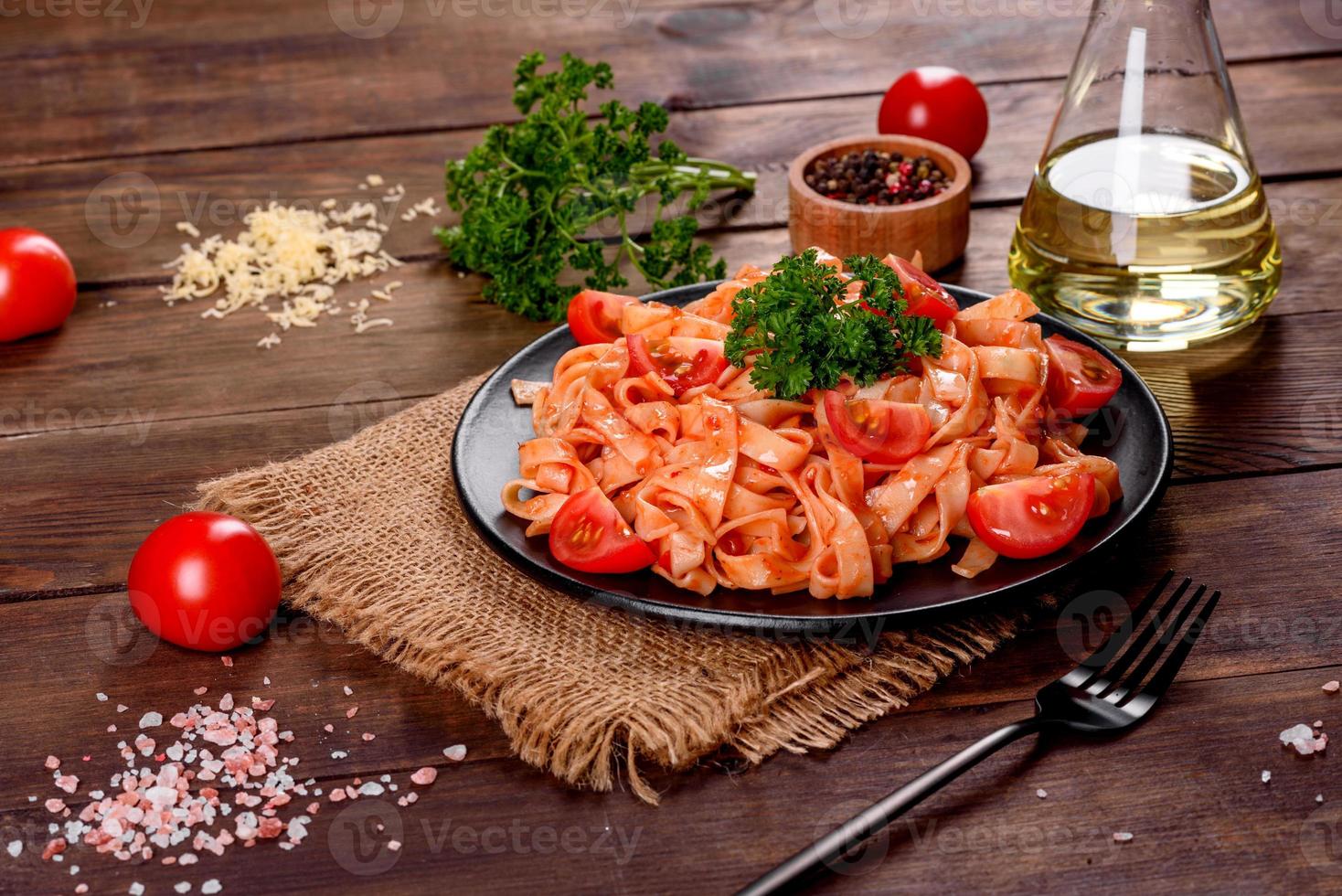 köstliche frische Paste mit Tomatensauce mit Gewürzen und Kräutern auf dunklem Hintergrund foto