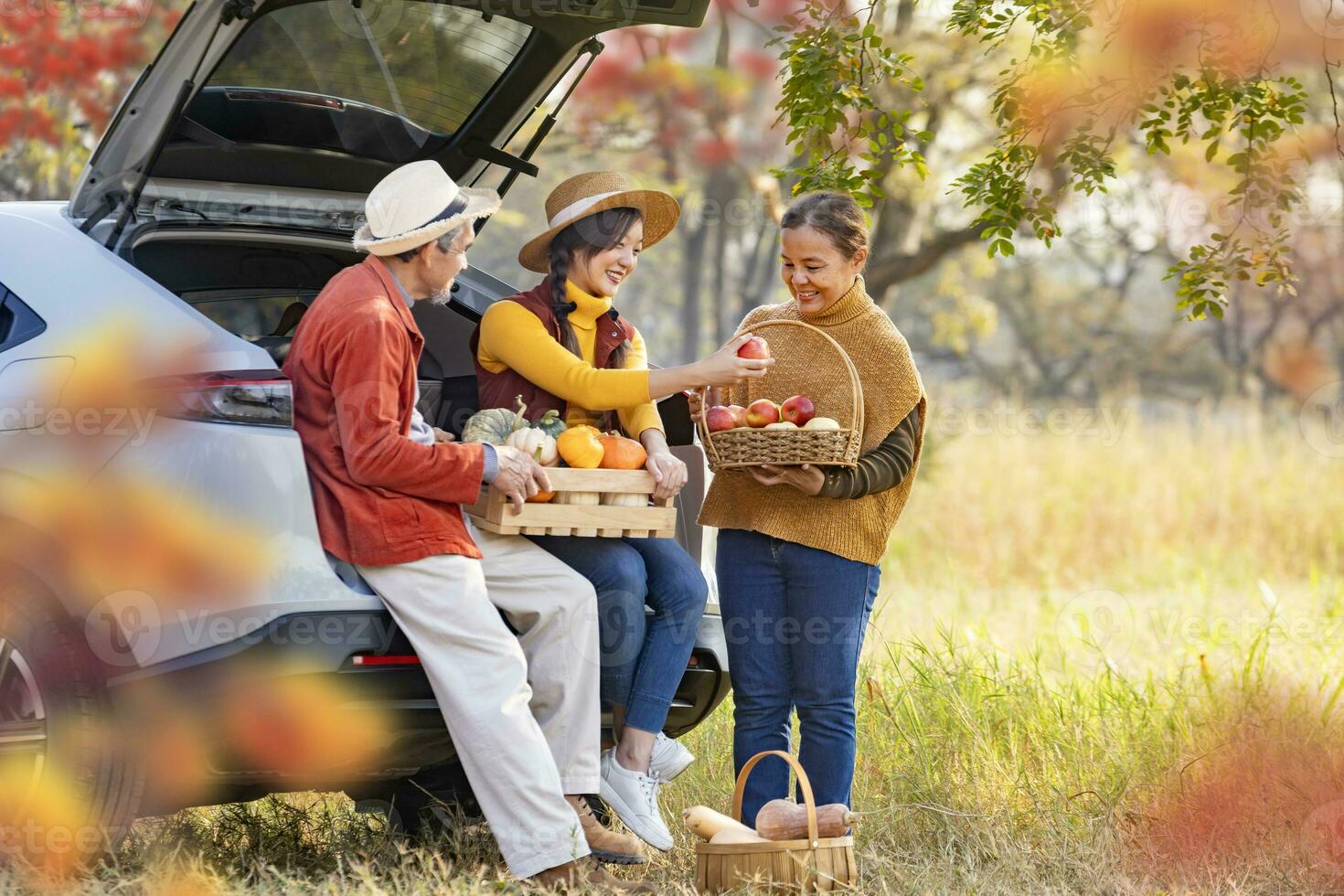 glücklich Farmer Familie Tragen Bio einheimisch produzieren Ernte mit Apfel, quetschen und Kürbis während Verkauf beim das Auto Kofferraum im lokal Markt mit fallen Farbe von Ahorn Baum während Herbst Jahreszeit foto