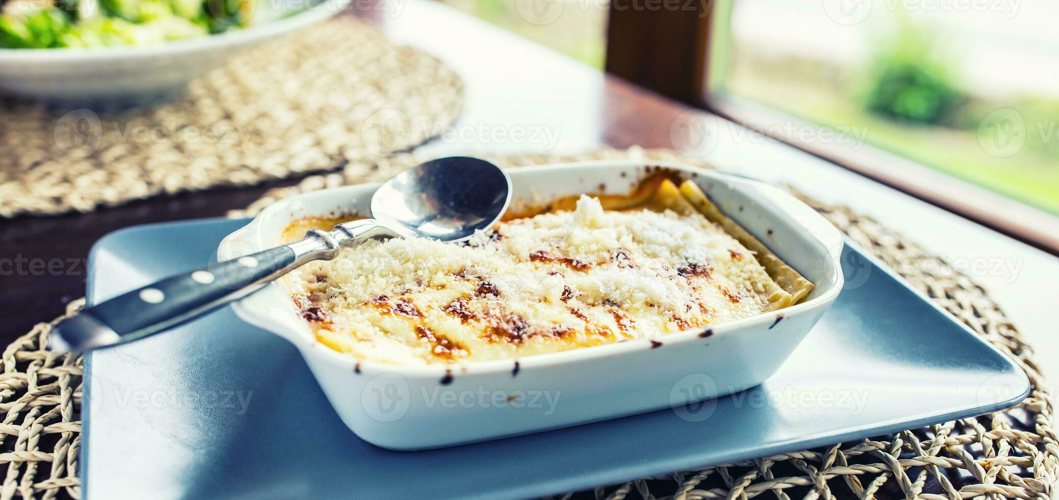 Portion von Lasagne Bolognese im Gericht auf Tabelle im Restaurant foto