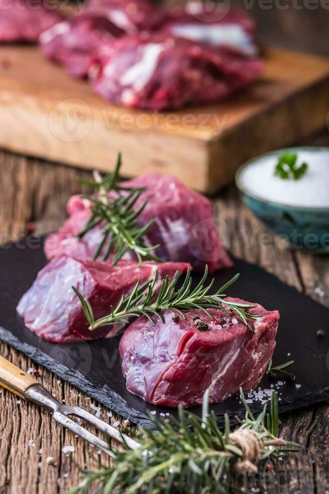 roh Rindfleisch Fleisch. roh Rindfleisch Filet Steak auf ein Schneiden Tafel mit Rosmarin Pfeffer Salz- im andere Positionen. foto