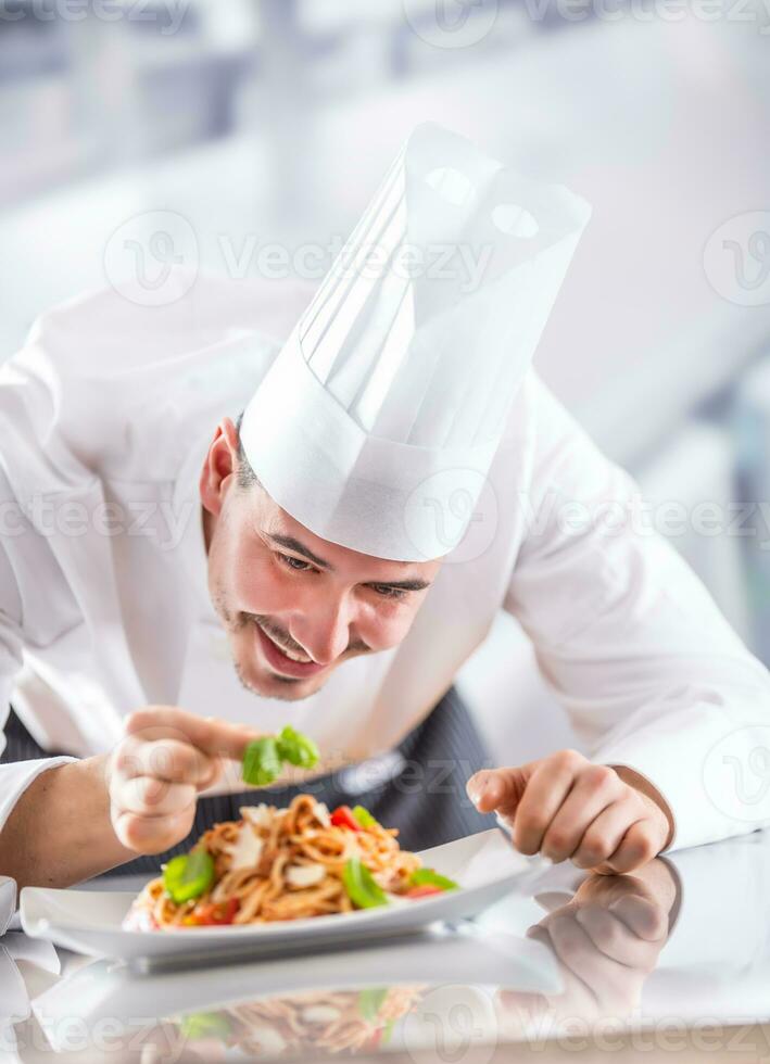 Koch im Restaurant Küche bereitet vor und dekoriert Mahlzeit mit Hände. Koch vorbereiten Spaghetti Bolognese foto