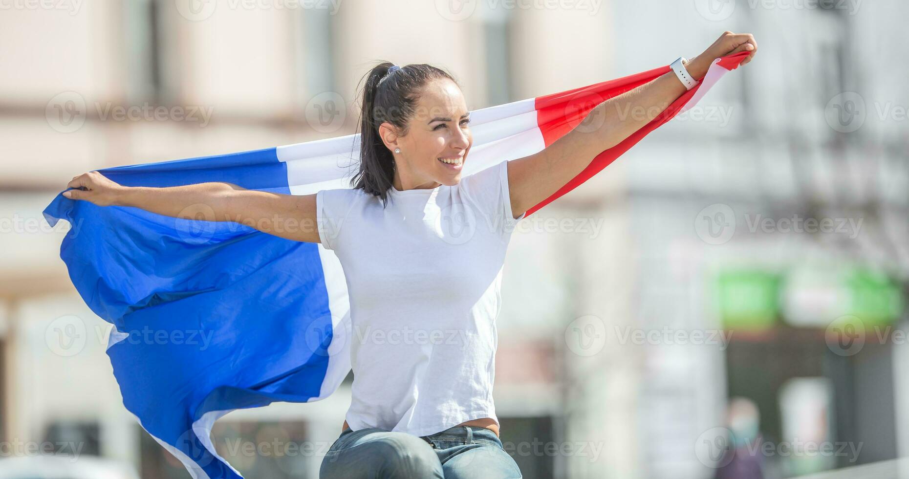 schön Frau sieht aus zu das Seite lächelnd, halten ein Flagge von Frankreich hinter ihr foto