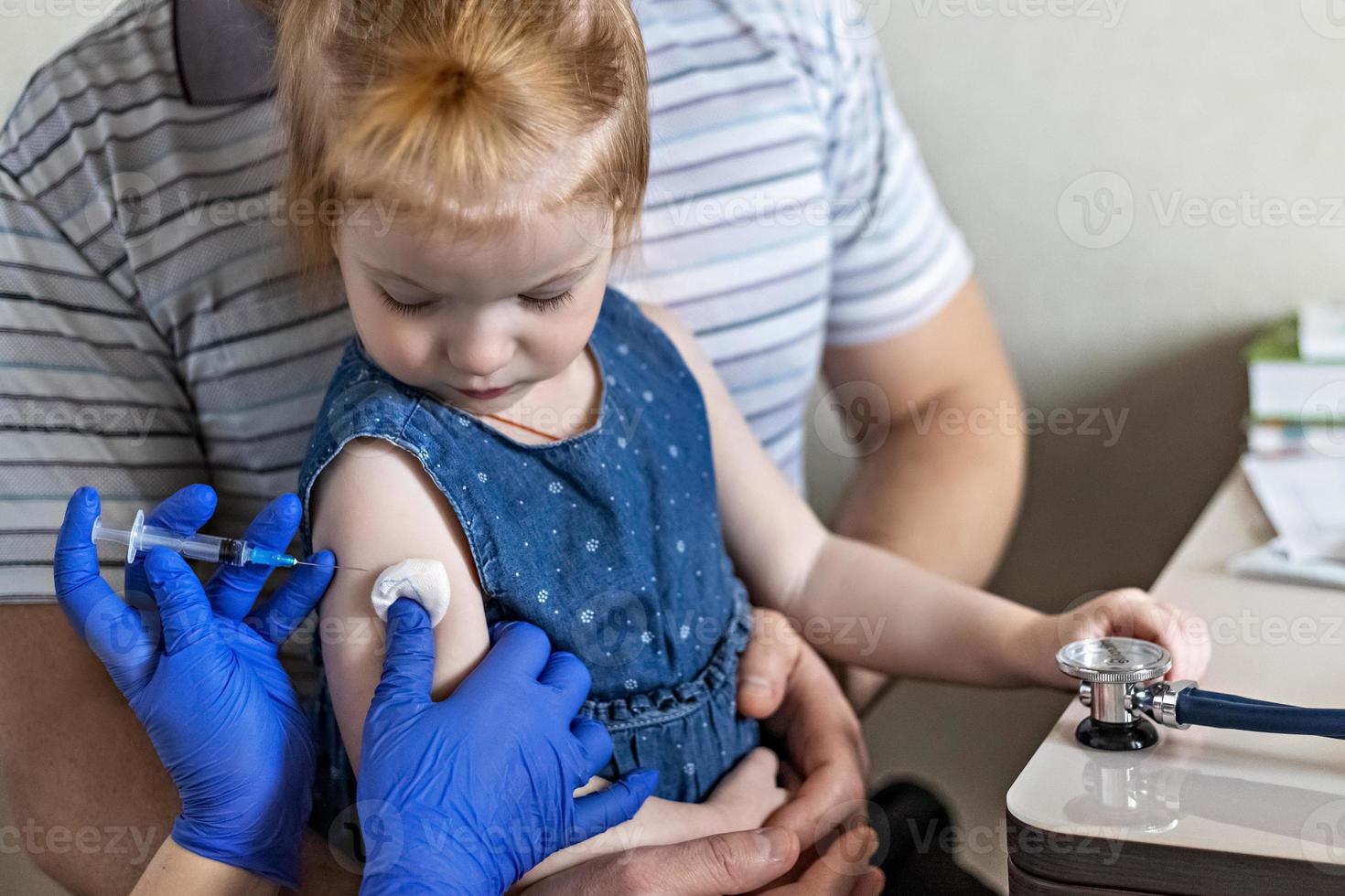 ein kleines Mädchen mit ihrem Vater in der Arztpraxis der Klinik wird gegen das Coronavirus geimpft foto