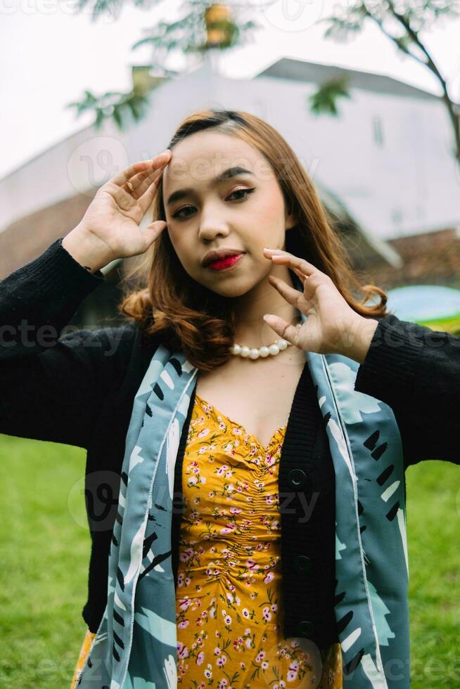 ein Frau im ein schwarz Jacke und Orange Kleid Stehen schön im das Hinterhof foto