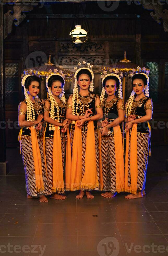 ein Gruppe von javanisch Tänzer Stehen mit ihr freunde während tragen Gelb Kostüme und Schals foto