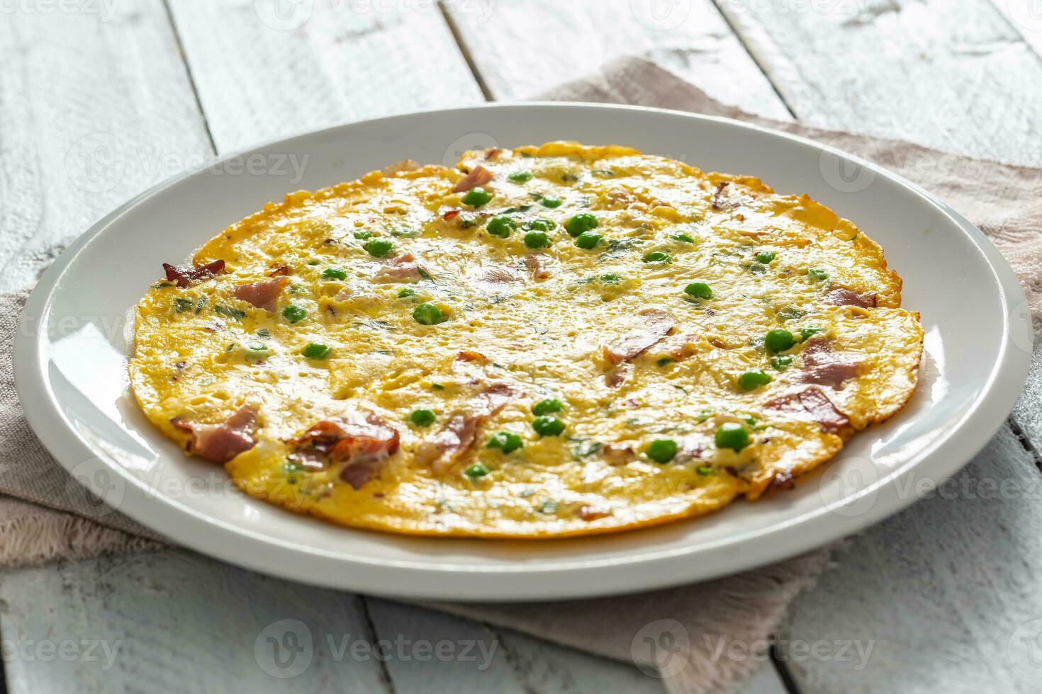Omelette mit Prosciutto Erbsen und Kräuter auf Weiß Teller foto