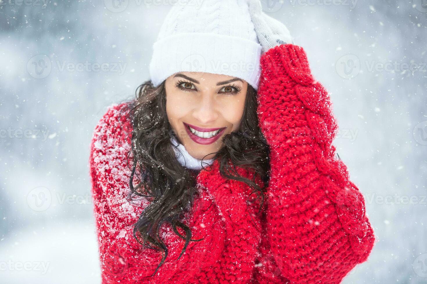 modisch Frau gekleidet im warm Winter gestrickt Oberbekleidung lächelt beim das Kamera während schneebedeckt Winter kalt Tag foto