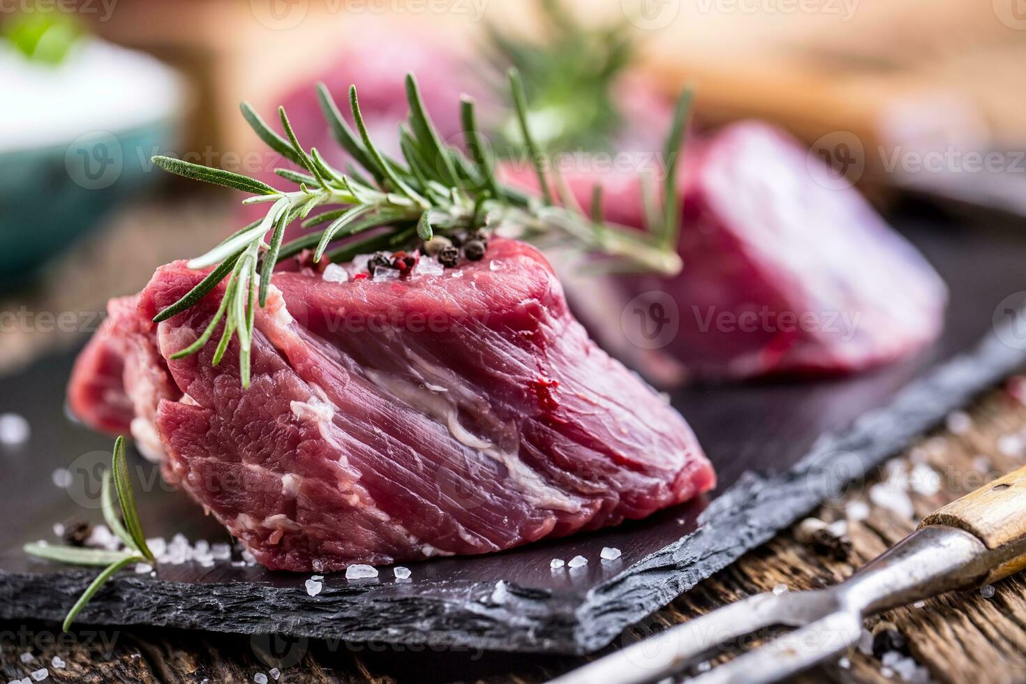 roh Rindfleisch Fleisch. roh Rindfleisch Filet Steak auf ein Schneiden Tafel mit Rosmarin Pfeffer Salz- im andere Positionen. foto