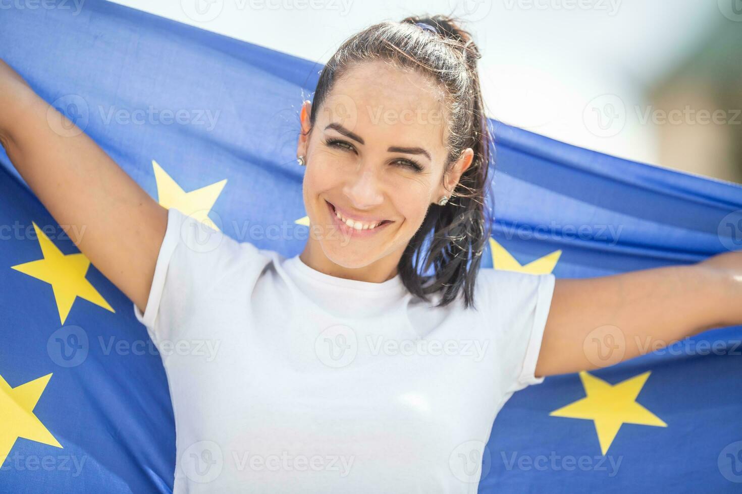 lächelnd schön Frau halten ein EU Flagge suchen beim das Kamera foto