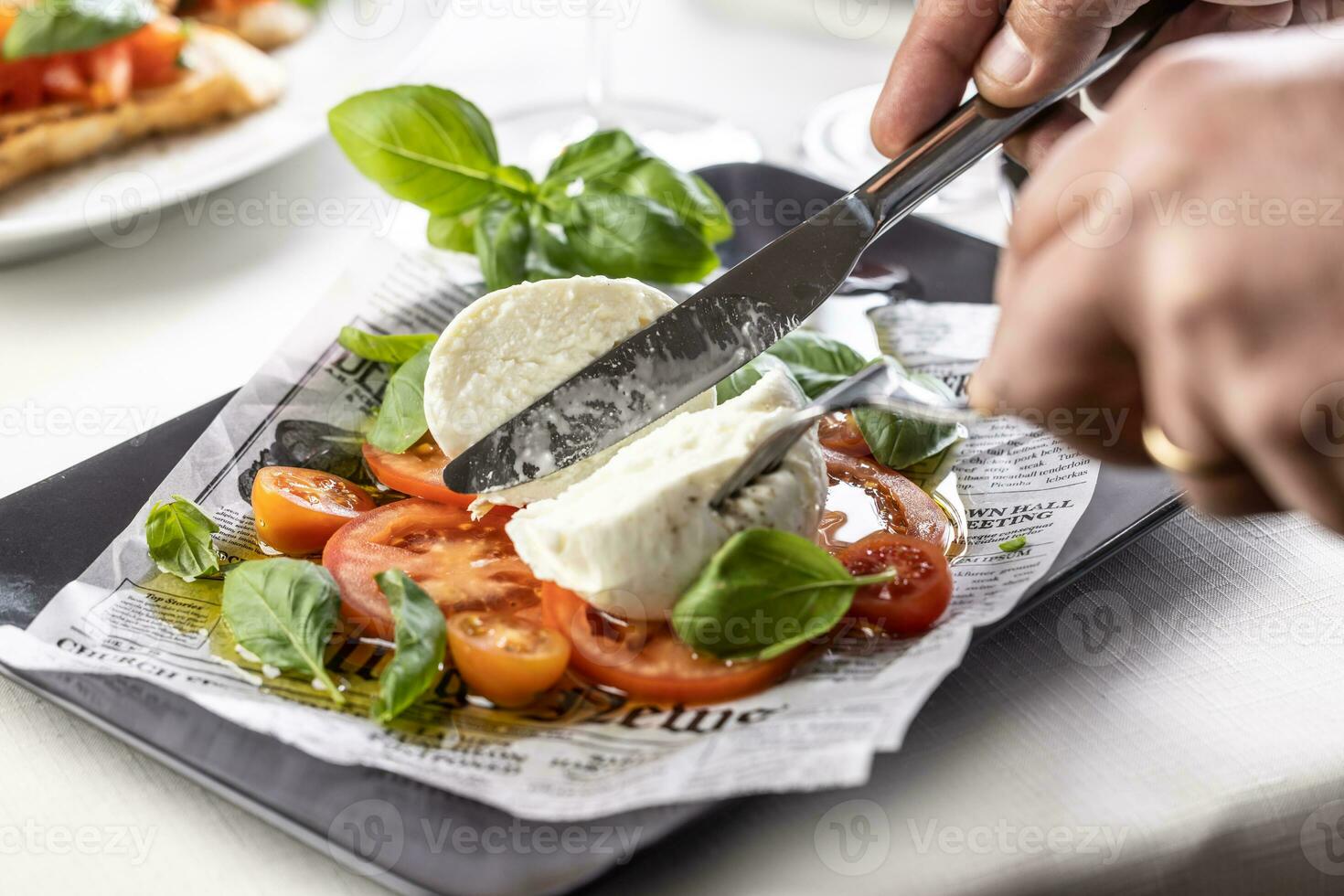 Büffel Mozzarella Teilt im Hälften durch Besteck auf ein Original Caprese Salat foto