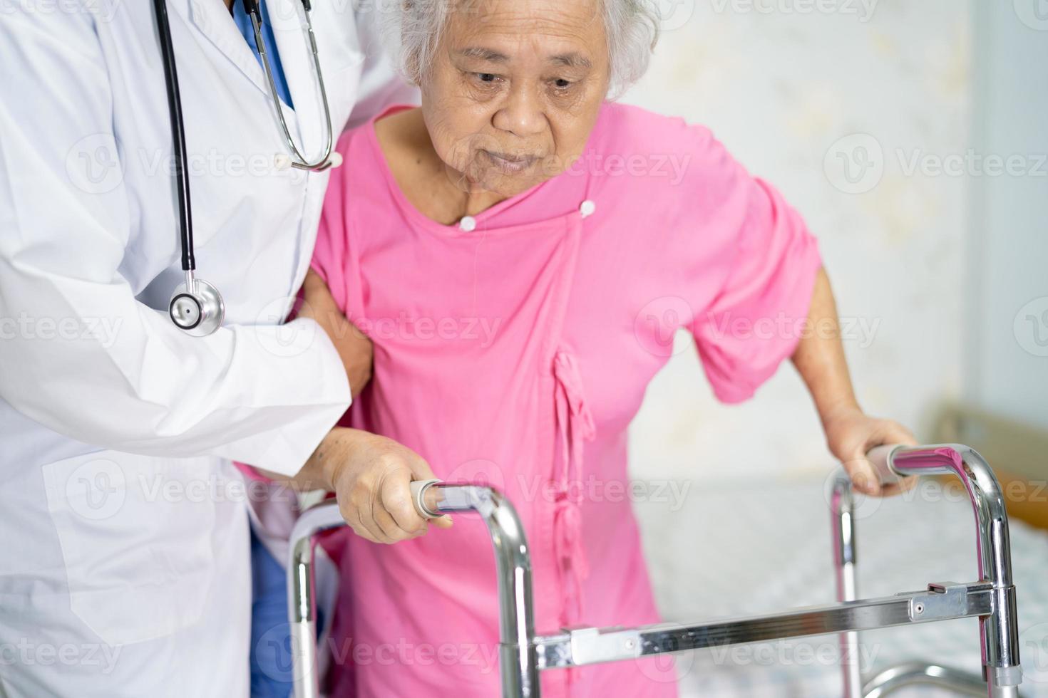 asiatische krankenschwester physiotherapeut arztpflege, hilfe und unterstützung älterer oder älterer alter frauenpatienten gehen mit walker auf der krankenstation, gesundes starkes medizinisches konzept. foto