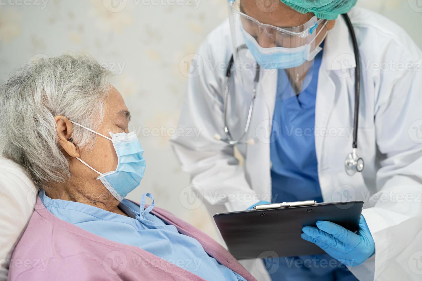 Arzt, der ein Stethoskop verwendet, um asiatische Senioren oder ältere Frauen mit einer Gesichtsmaske im Krankenhaus zu überprüfen, um die Infektion mit dem Covid-19-Coronavirus zu schützen. foto