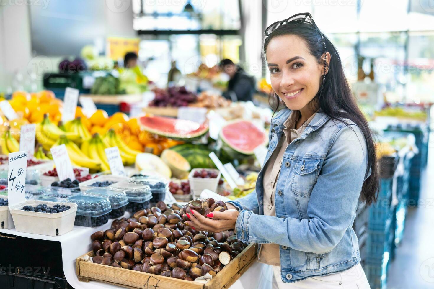 schön Frau hält Hand voll von Kastanien im das Bauern Markt foto