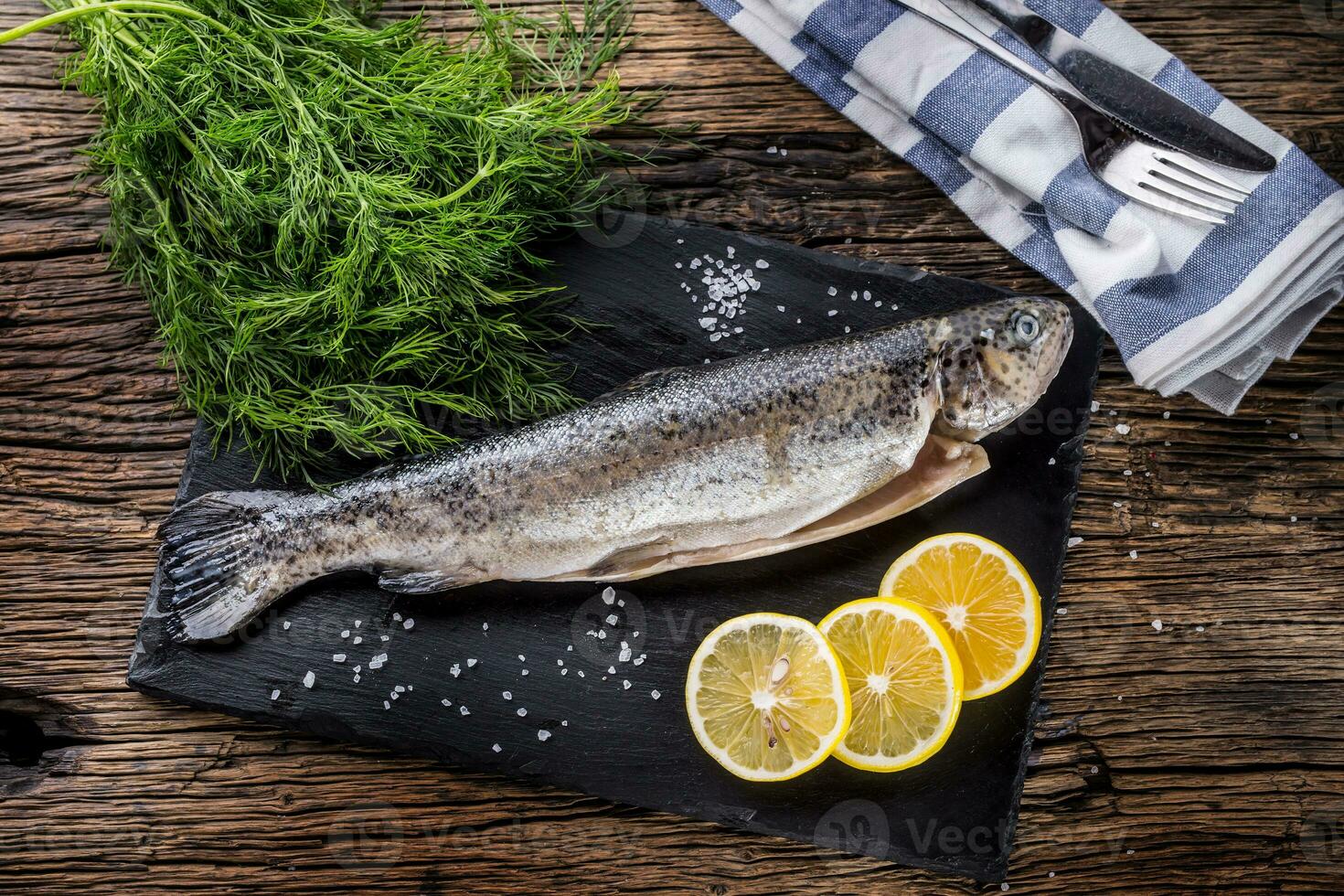 roh Fisch Forelle mit Kräuter Dill Zitrone und Salz- auf rustikal Eiche Tabelle foto