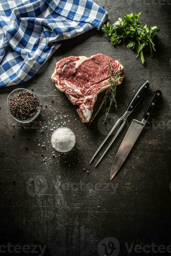 Rippe Auge Steak mit Knochen auf Metzger Tafel mit Kräuter Salz- Pfeffer Gabel und Messer foto