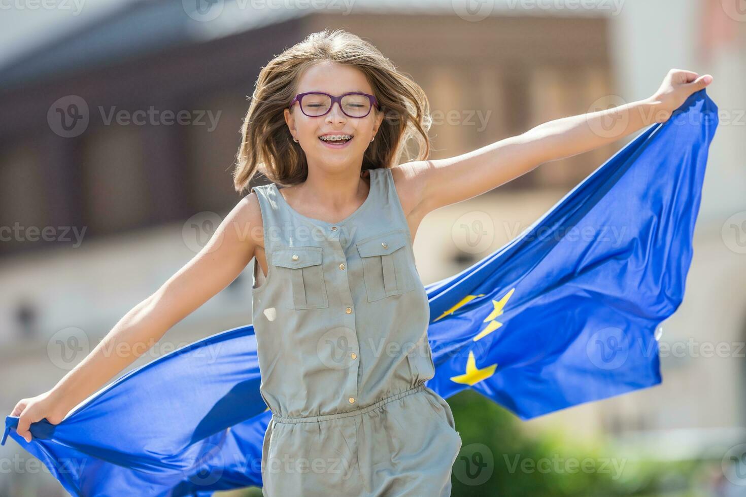 EU Flagge. süß glücklich Mädchen mit das Flagge von das europäisch Union. jung Teenager Mädchen winken mit das europäisch Union Flagge im das Stadt foto