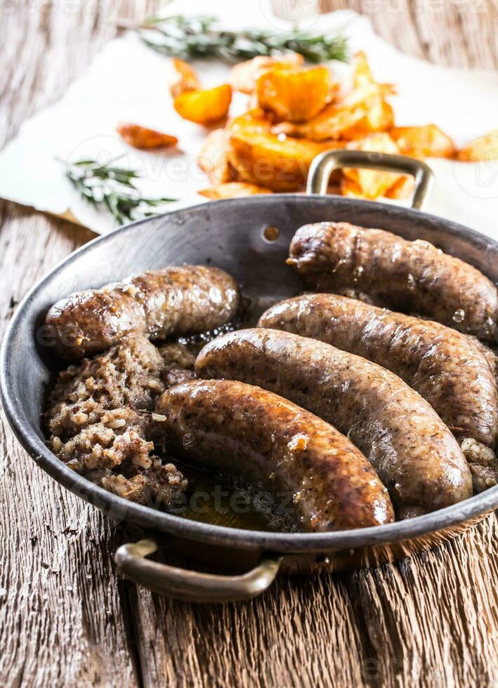 Würstchen.gebraten Schweinefleisch Würstchen im ein schwenken mit Kartoffeln und Rosmarin. foto