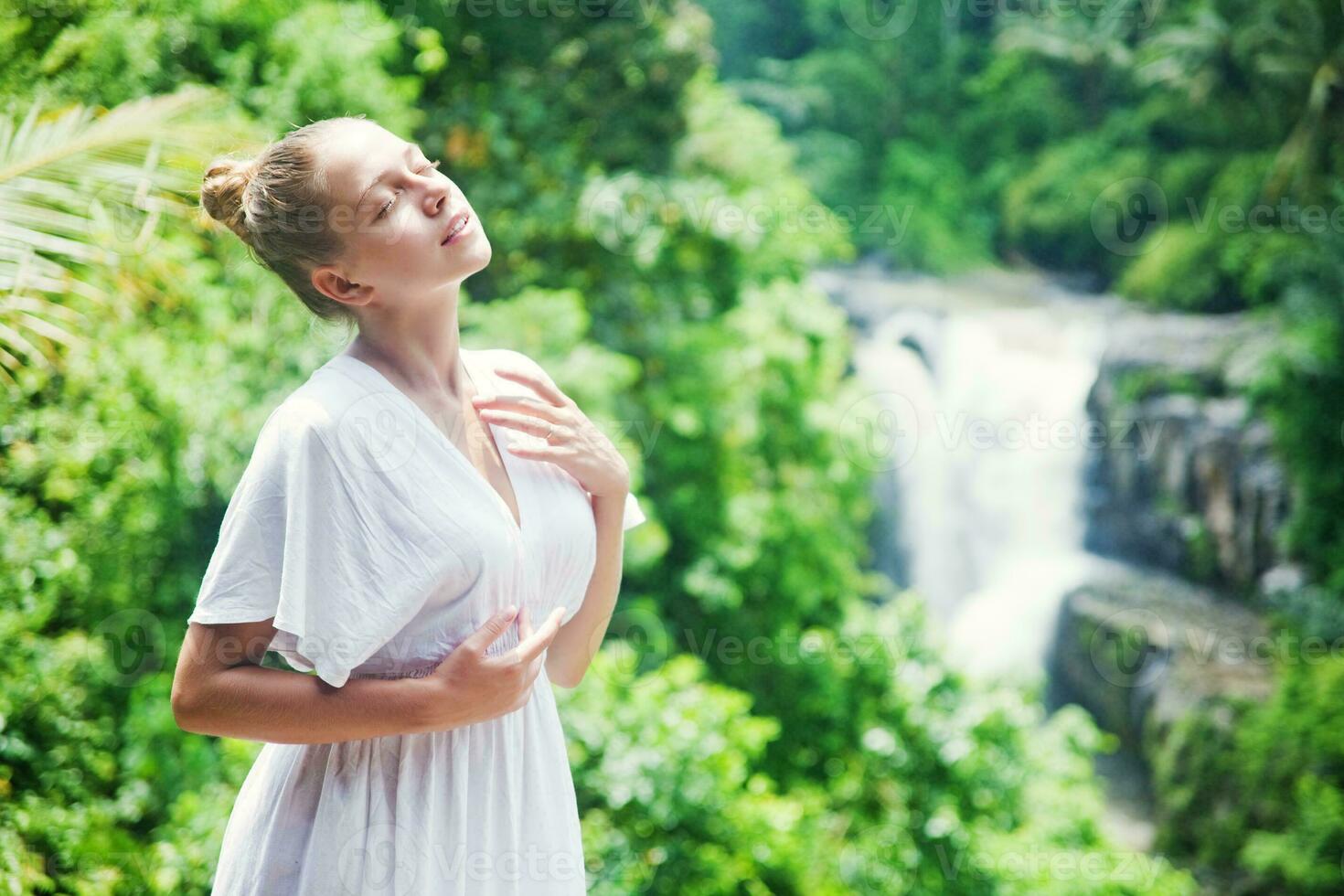 schön Frau im Weiß Kleid Stehen im Vorderseite von Wasserfall foto
