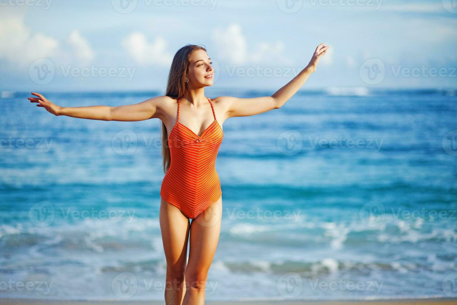 ein Frau im ein Orange Badeanzug Stehen auf das Strand foto