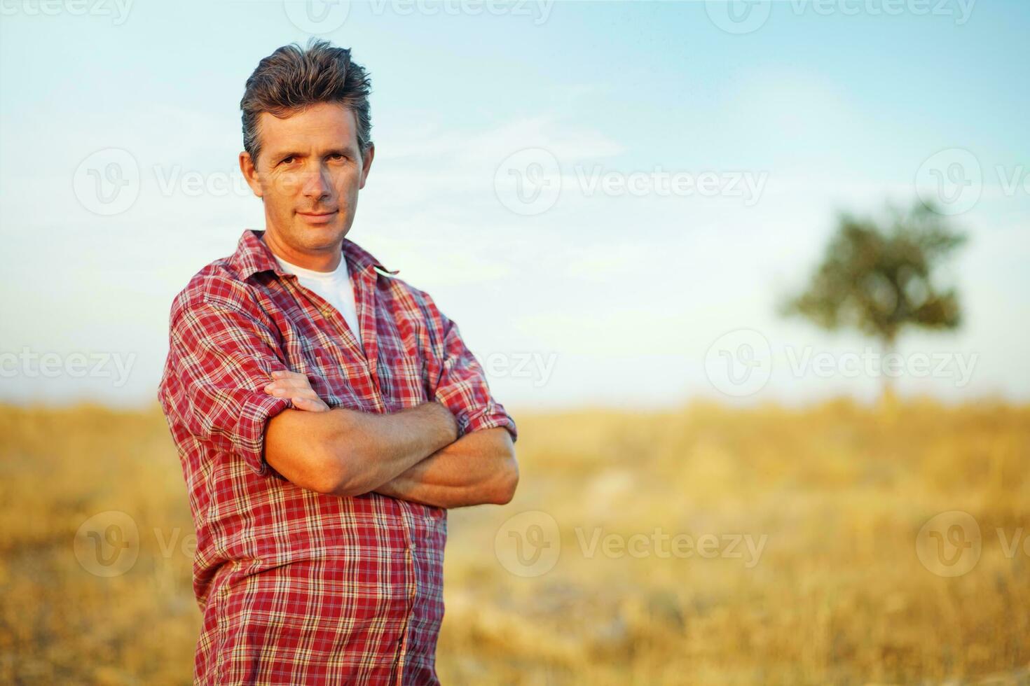 ein Mann Stehen im ein Feld mit seine Waffen gekreuzt foto