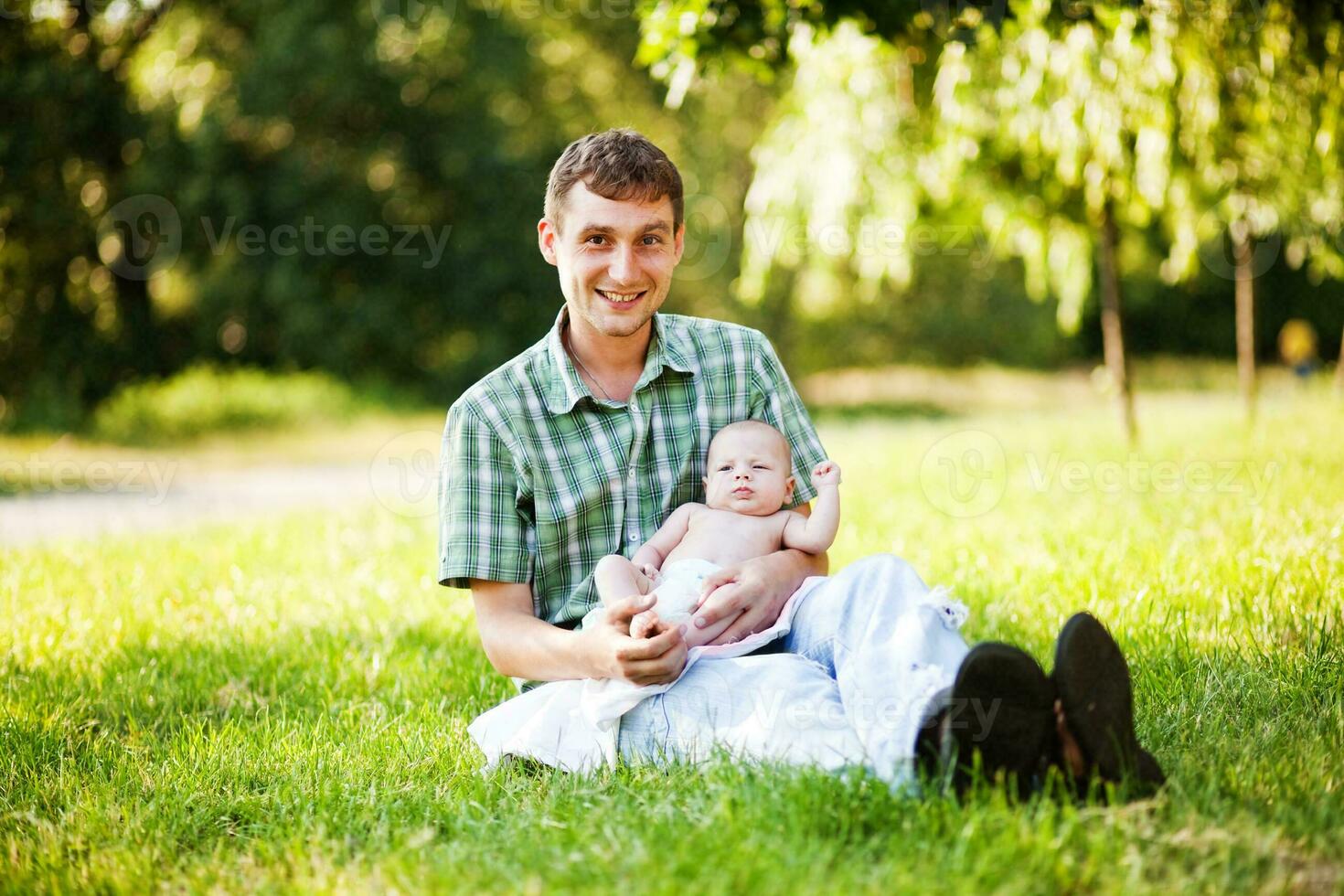 ein Mann und seine Baby sind Sitzung im das Gras foto