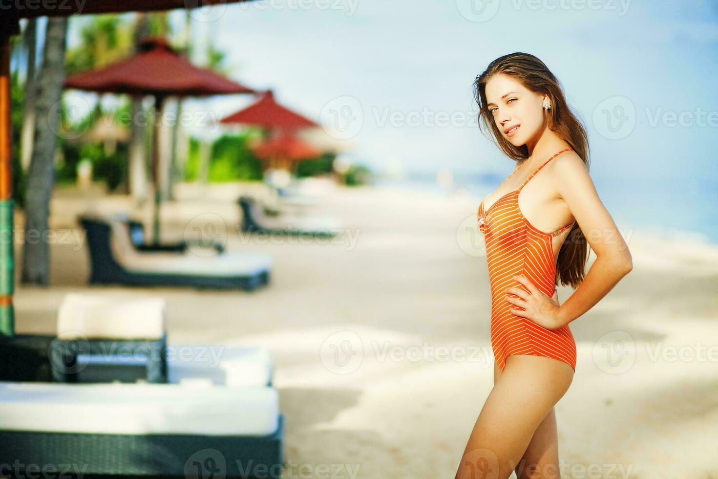 ein Frau im ein Orange Badeanzug auf das Strand foto